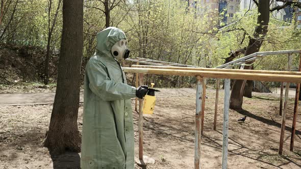 A Man in a Protective Chemical Suit Treats a Playground with a Disinfectant. Man, Worker Disinfects