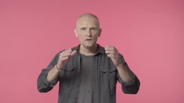 Shocked Elderly Bald Man Reacting Startled and Anxious Hold Hands on Head and Nervously Staring alt