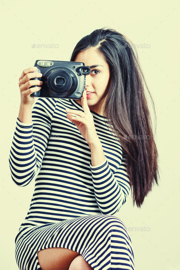 Young girl wearing casual cloth posing with instant camera.