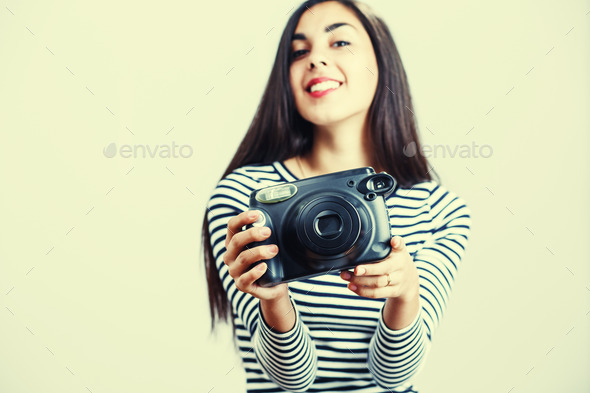 Young girl wearing casual cloth posing with instant camera.