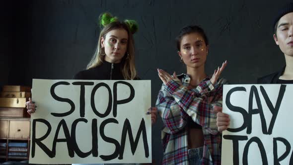 The Girl Shows the Cross with Her Hands and Others are Holding Stop Racism Banners alt