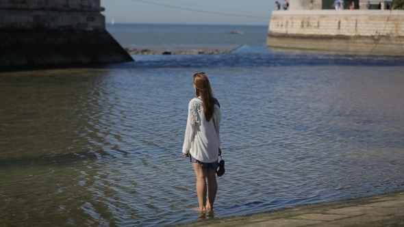 Young Woman Sightseeing, Walking Shoeless In Water alt