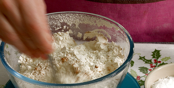 Woman Measures Spices into a Bowl of Flour