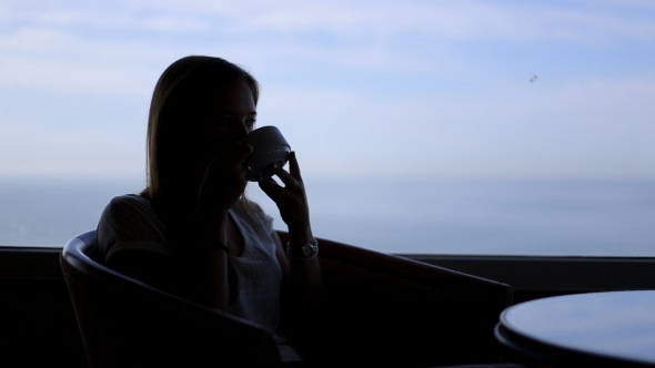 Silhouette Of Young Beautiful Woman Sits In a Cafe alt