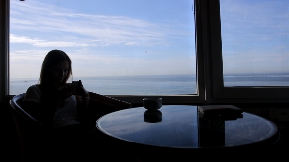 Silhouette Of Young Girl Sits In a Cafe alt