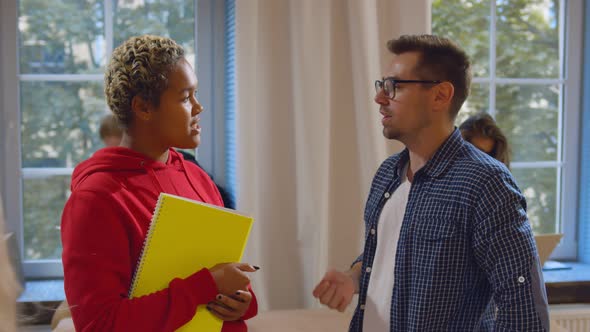 Happy Student Hugging Friend and Chatting Standing in University Common Room alt
