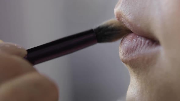 Makeup Artist Is Applying Base Tone on Lips Using Brush Closeup Side View