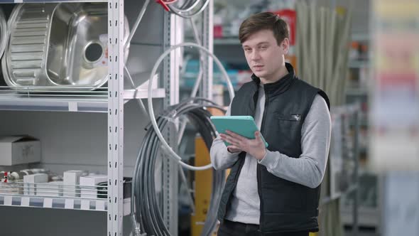 Portrait of Young Caucasian Hardware Store Manager Using Tablet and Thinking alt
