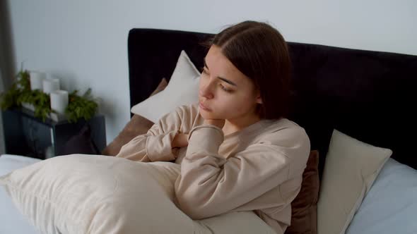 Upset Lovely Young Female with Birth Hands Anomaly Hugging Pillow at Home alt