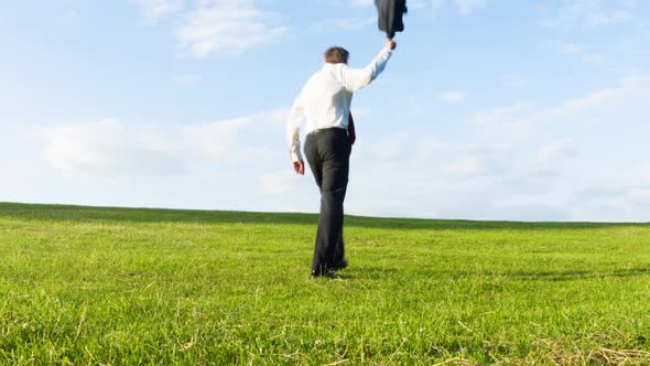 Businessman throwing his jacket off and running over a hill