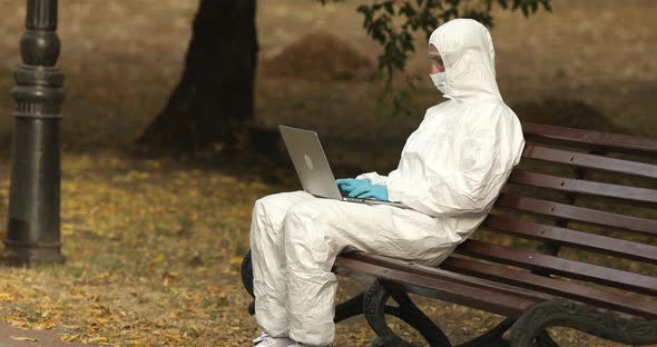 Portrait of caucasian man in white protective costume working on laptop.