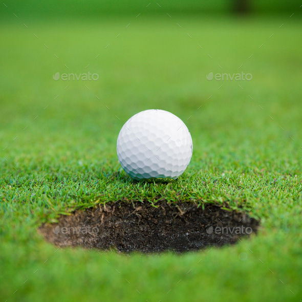 golf ball on lip of cup.  Golf ball and hole - Stock Photo - Images