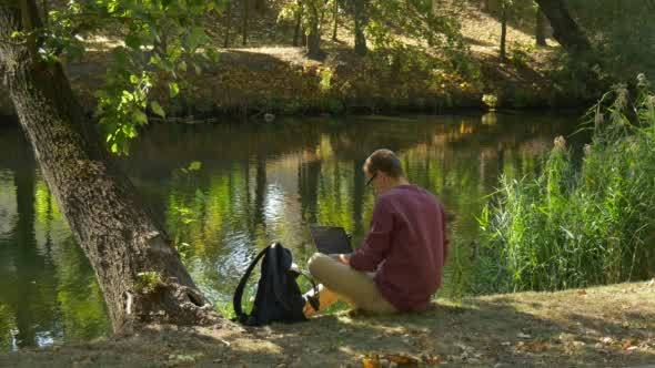 Man With Laptop Has Stood Up From Horizontal Tree alt