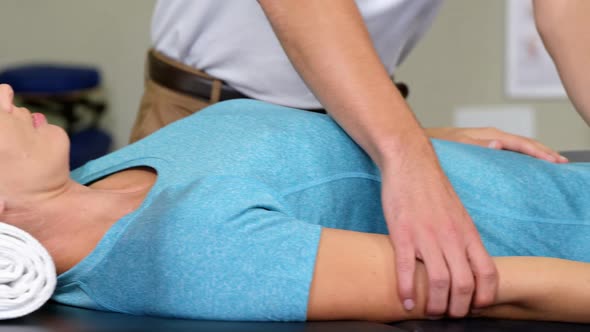 Male physiotherapist giving arm massage to female patient alt