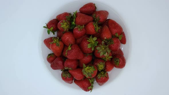 Strawberries on a plate rotating on a white background. Strawberry ripe season
