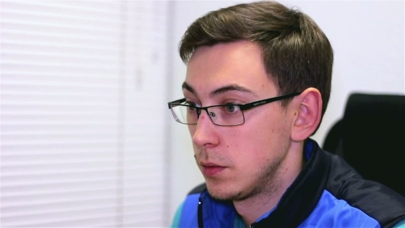 A Young Man In Glasses Works Behind a Computer