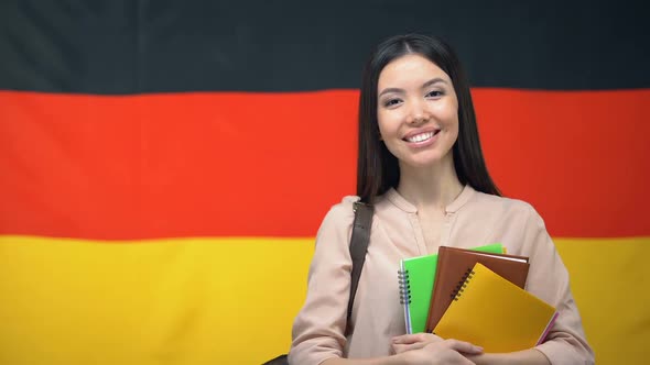 Happy Female Student Holding Copybooks Against German Flag Background, Education alt