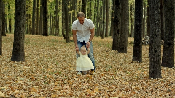 Father And His Baby Make First Step In Autumn Park alt