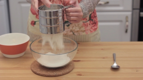 Women's Hands Sifting Flour Into a Bowl