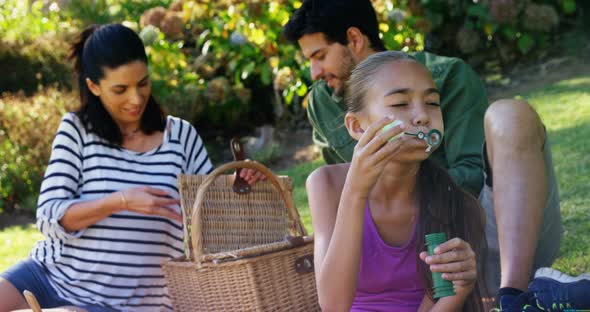 Girl blowing bubble while her parents sitting in background 4k alt