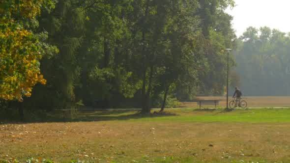 Man With Backpack Comes By Bicycle to The Bench alt