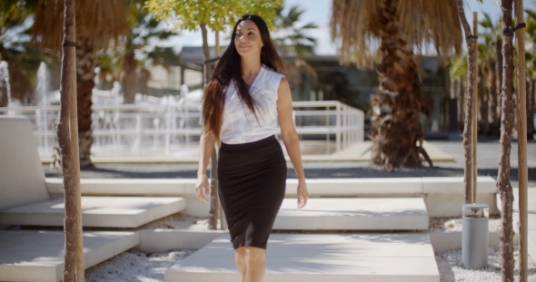 Elegant Young Woman Walking Through a Park alt