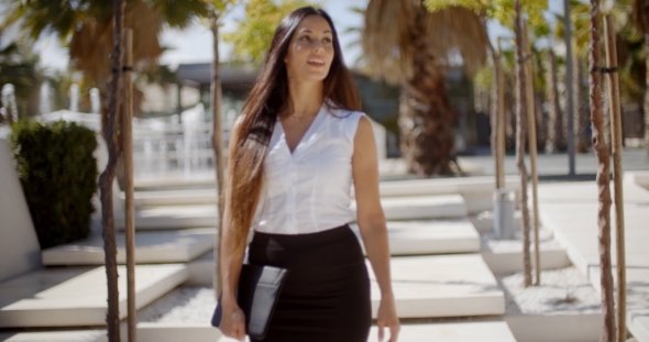 Young Businesswoman Walking Through a Park alt