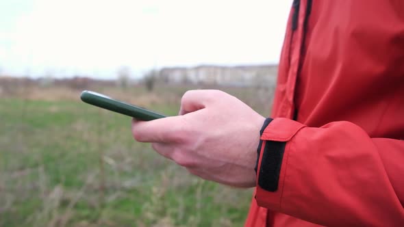 A Man Uses a Smartphone Surf the Internet on the Street