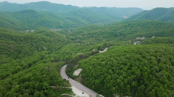 Aerial Fly Over Caucasian Mountains and Winding Road with Cars alt