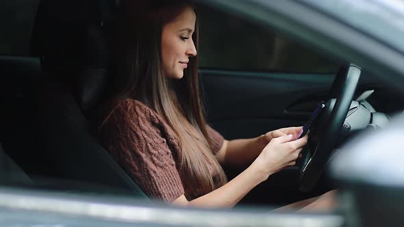 Smiling woman in car using smartphone