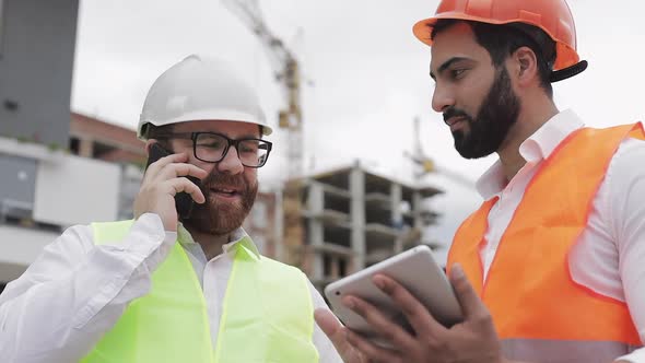 Happy Engineer Speaks on Mobile Phone on Construction Site and Checks the Work of the Worker alt