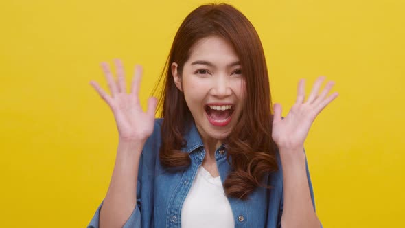 Portrait of young Asian lady with positive expression, excited screaming over yellow background alt