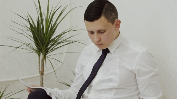 Businessman Sitting In a Chair Reading a Fashion