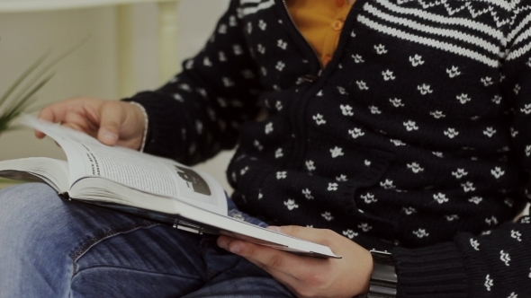 Guy In a Sweater Reading a Book Sitting On a Chair