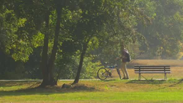 Man With Backpack is Standing at The Bench alt