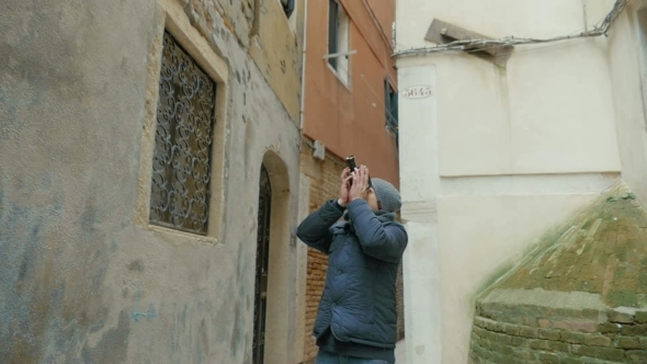 Man Filming Old Architecture With Retro Camera alt