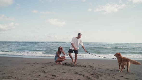 Couple Playing with Dog Near Ocean alt