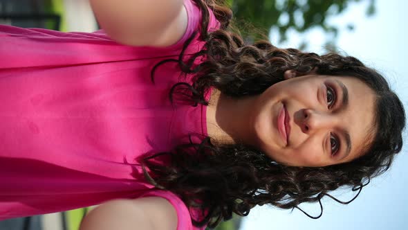 Vertical Happy Mixed Race Girl Pink Tshirt Talks Via Video Link on Smartphone alt