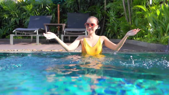 Young asian woman enjoy around outdoor swimming pool for leisure alt