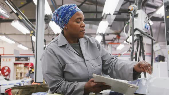 African American female car mechanic painting a body of a car alt