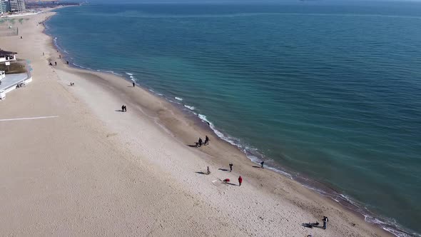 Beautiful aerial view of a drone, city beach with people walking along the promenade.