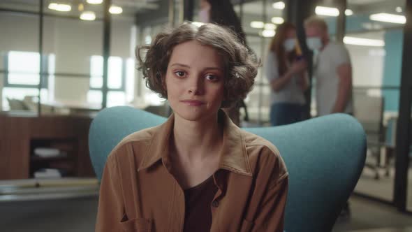 Sitting on the Chair in the University a Young Cute Student Looks at the Camera and Fixes Hair Slow alt