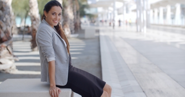 Elegant Woman Sitting On a Bench On a Promenade alt