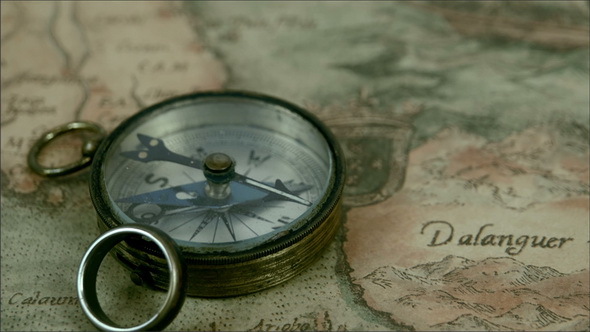 A Small Compass and a Ring on Top of a Map