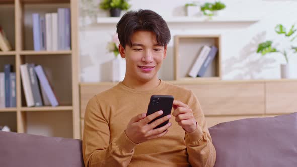 Asian man is smiling on the cellphone like he got a good news. The man seems so happy with the mobil alt