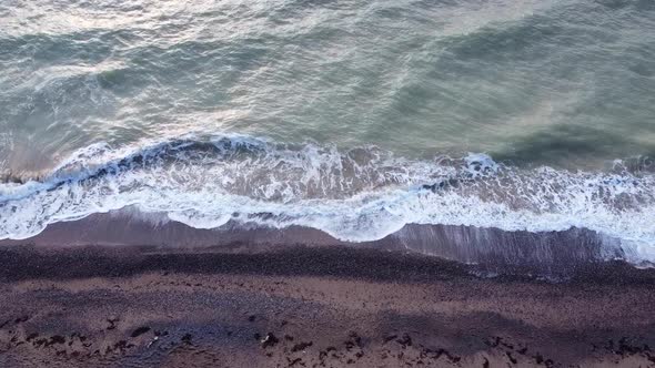 Aerial top view of ocean waves break on a beach. Sea waves and sand beach aerial view drone shot