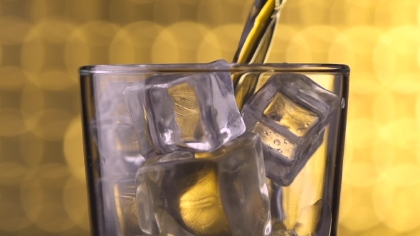 Glass With Ice Cubes And Pouring Whiskey