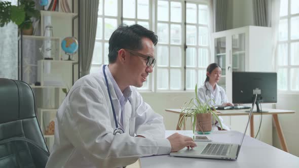 Asian Male Doctor Communicates With Patient By Video Link, Doctor Consults Patient alt