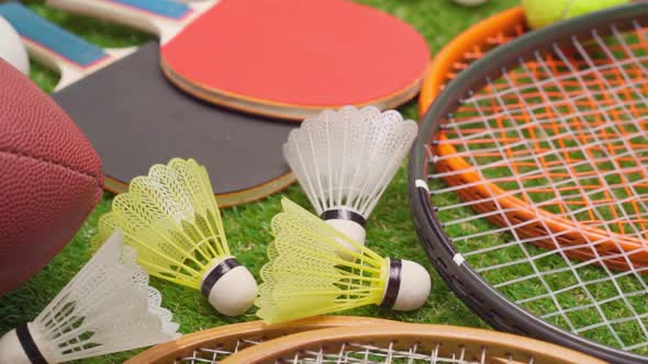 Various Sport Equipment on Grass Including Rackets Balls Shuttlecocks and Ball Close Up alt