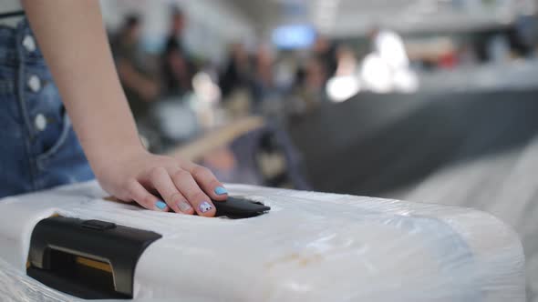 Closeup Hand of a Teenage Girl with a Youth Manicure is Lying on the Suitcase on the Airport alt
